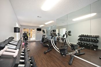 a gym with cardio machines and weights on a wooden floor